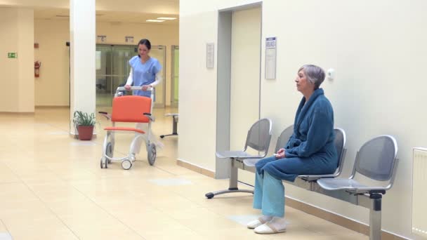Hemşire hastanede tekerlekli sandalye ile bekleyen hasta için geldiğinde — Stok video