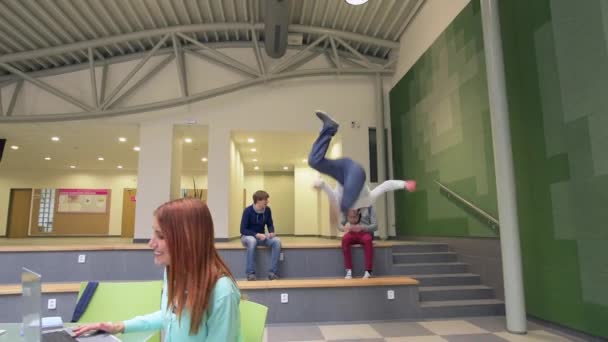 Estudantes em menino corredor da faculdade faz salto parkour — Vídeo de Stock