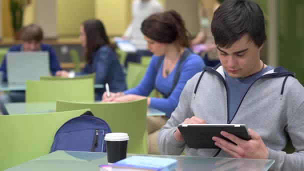 Adolescente niño escribiendo en la tableta en la sala de la escuela moderna — Vídeos de Stock