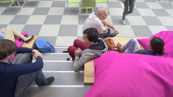 Students with professor sitting on stairs in college hall — Stock Video