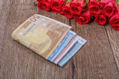 Euro paralar ve gül ahşap arka plan üzerinde