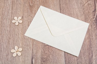 Ahşap arka planda zarf ve çiçekler