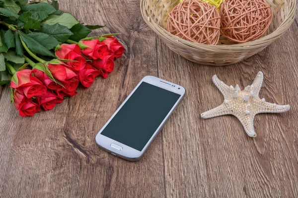 Teléfono móvil, estrellas de mar blancas y rosas sobre un fondo de madera — Foto de Stock