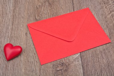 Kırmızı zarf ve ahşap arka plan üzerinde kalp