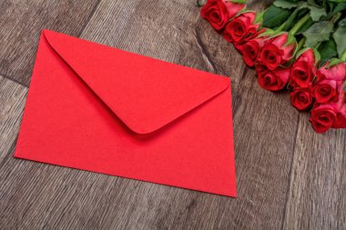 Kırmızı zarf ve gül ahşap arka plan üzerinde