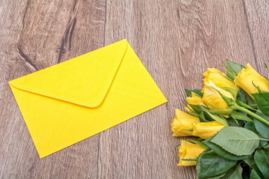 Sarı zarf ve gül ahşap arka plan üzerinde