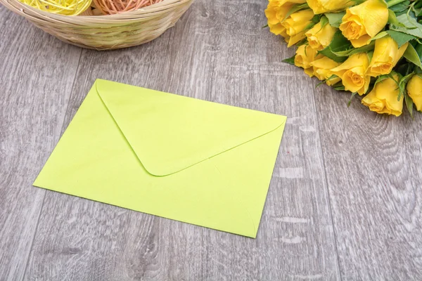 Ljusa gröna kuvertet och rosor på en trä bakgrund — Stockfoto