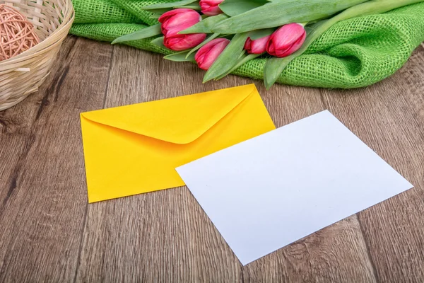 Briefumschlag mit Blatt Papier und Tulpen auf Holzgrund — Stockfoto