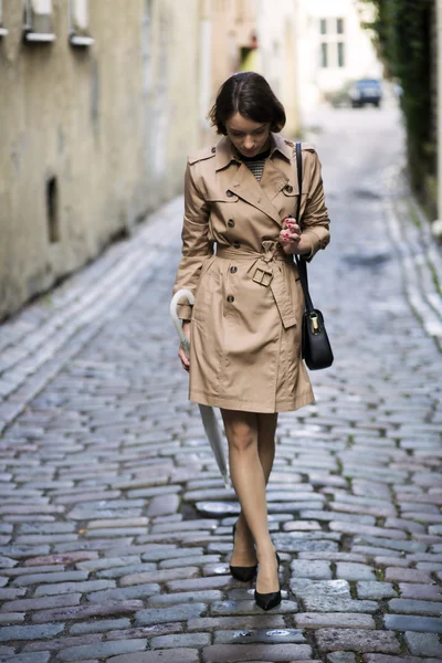 Donna a cappotto beige con borsa alla ricerca di scarpe — Foto Stock