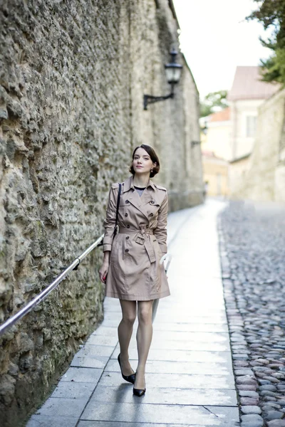 Vrouw op beige jas in de buurt van de oude stadsmuur — Stockfoto