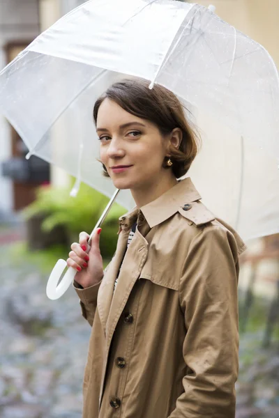 Frau im beigen Mantel hält weißen Regenschirm offen — Stockfoto