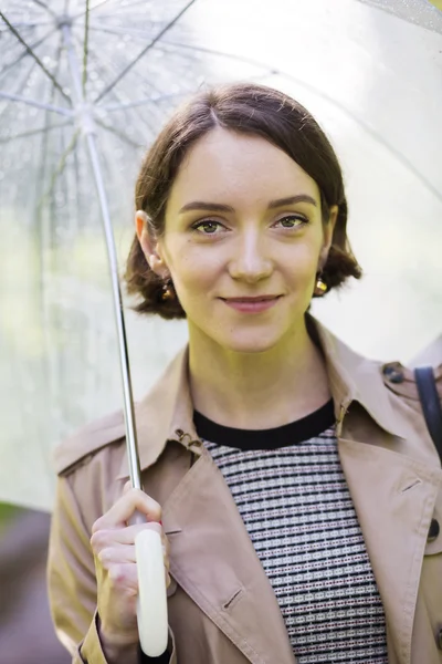 Woman at coat under umbrella since it rains — Stock Photo, Image