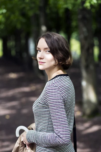 Woman at striped dress and coat at hand — Stock Photo, Image