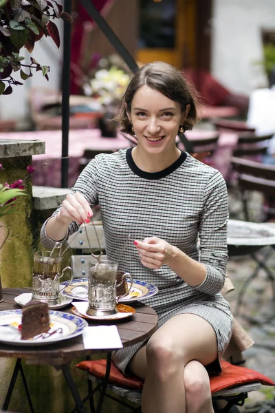 Mulher no café de rua faz chá e sorri — Fotografia de Stock