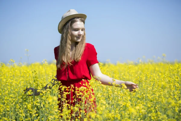 Kvinna i röd klänning mellan gula växter — Stockfoto