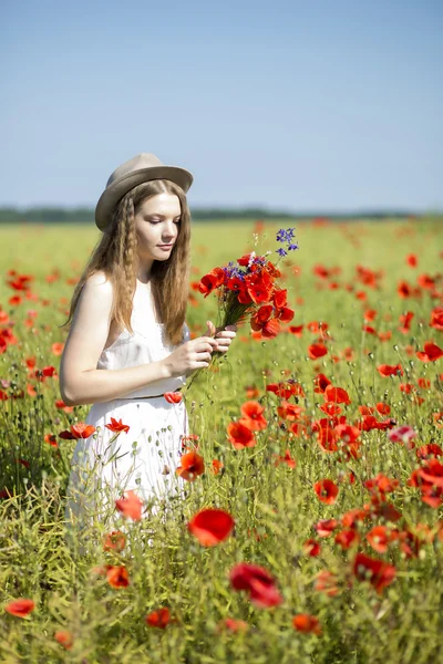 Vrouw aan het witte jurk verzamelt poppy boeket — Stockfoto