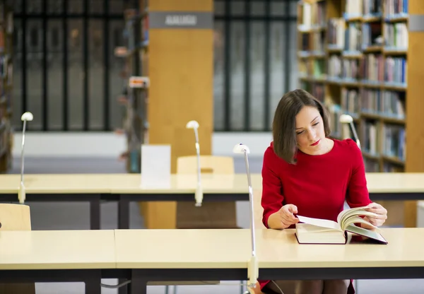 Frau in Bibliothek sucht Wissen aus Buch — Stockfoto