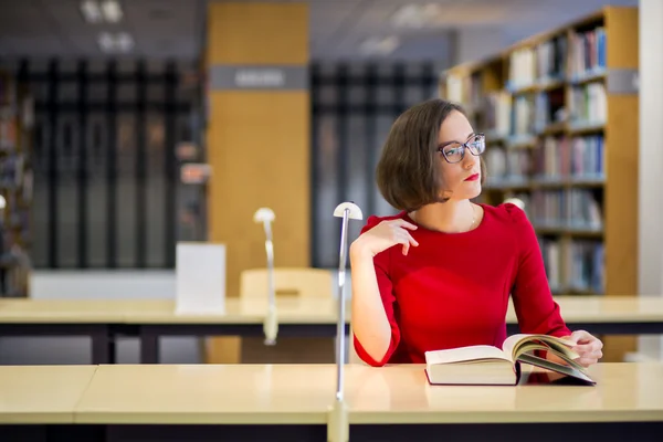 Mulher com óculos na biblioteca olhando para a esquerda — Fotografia de Stock
