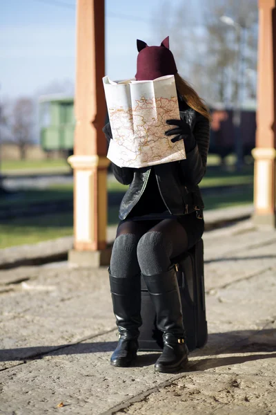 Женщина на станции прячет лицо за картой — стоковое фото