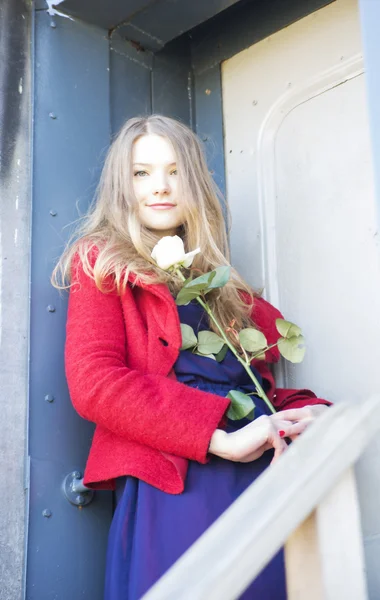 Vrouw met roos naast vlek deur — Stockfoto