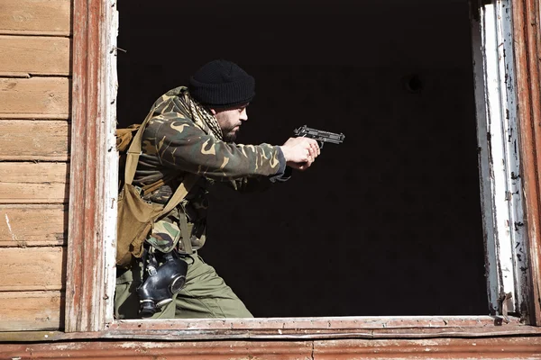 El hombre militar con un arma negra en sus manos tiene como objetivo disparar. — Foto de Stock