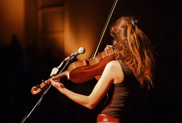 La elegante pelirroja toca el violín en la oscuridad — Foto de Stock