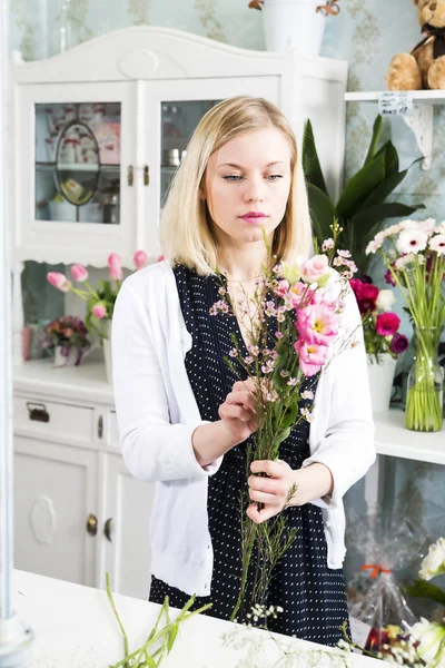 Mujer de aspecto serio creando la composición con flores — Foto de Stock