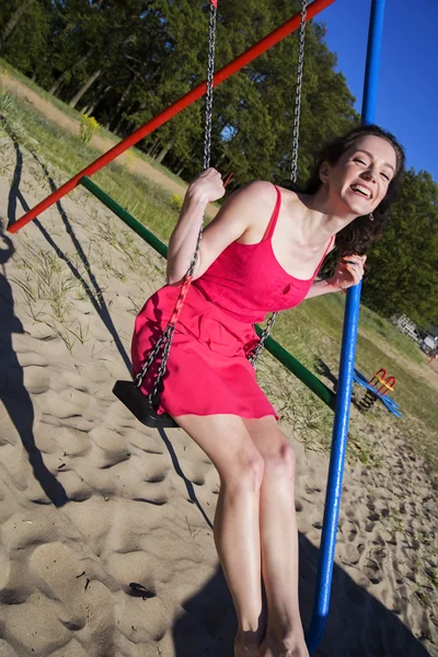 Mulher infantil feliz se diverte em balanços — Fotografia de Stock