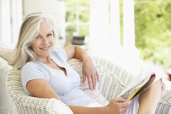Starszy kobieta siedzi czytania magazynu — Zdjęcie stockowe