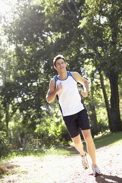 Hombre corriendo a lo largo del camino del bosque — Foto de Stock