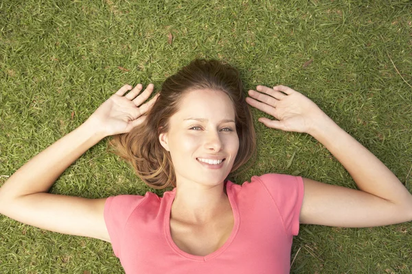 Jonge vrouw liggen in gras — Stockfoto