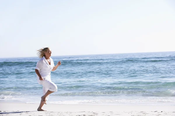 Seniorin läuft am Strand entlang — Stockfoto