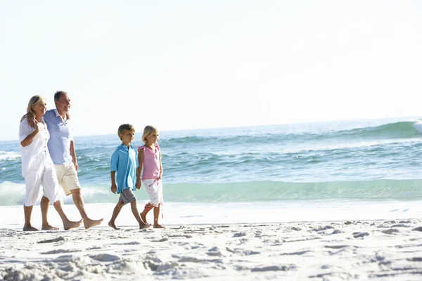 Бабушка с дедушкой и внуки прогуливаются вдоль пляжа — стоковое фото