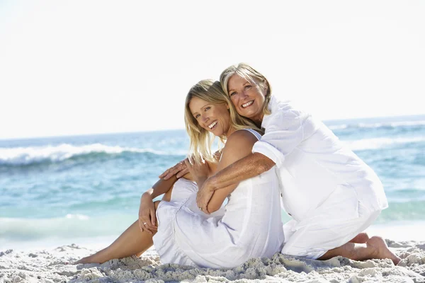 Moeder en dochter zittend op strand — Stockfoto