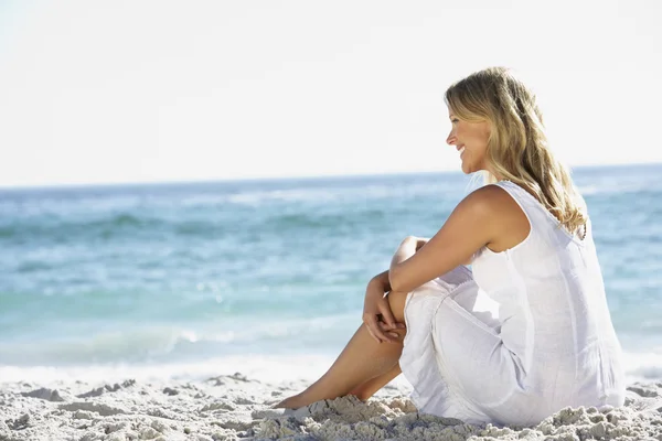 Ung kvinna sitter på stranden — Stockfoto