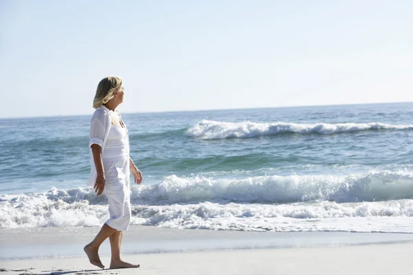 Äldre kvinna promenader längs stranden — Stockfoto