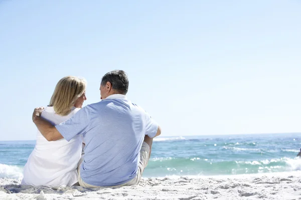 Couple âgé assis sur la plage de sable — Photo