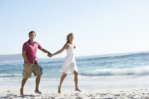 Молодая пара прогуливается вдоль песчаного пляжа — стоковое фото