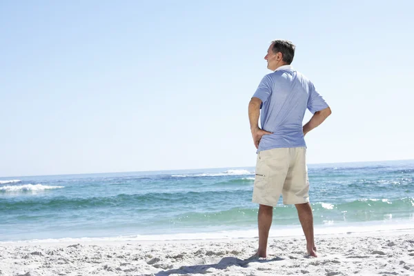 Starszy człowiek stojący na piaszczystej plaży — Zdjęcie stockowe