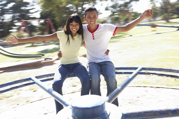 Pareja adolescente divirtiéndose en la rotonda — Foto de Stock