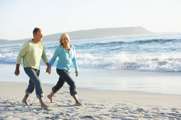 Äldre par promenader längs stranden — Stockfoto