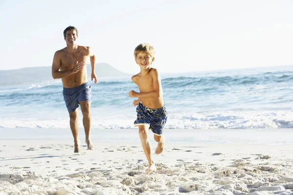 Padre e hijo corriendo a lo largo de la playa — Foto de Stock
