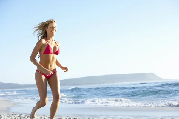 Femme courant le long de la plage de sable — Photo