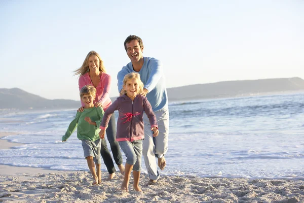 Família correndo ao longo da praia arenosa — Fotografia de Stock
