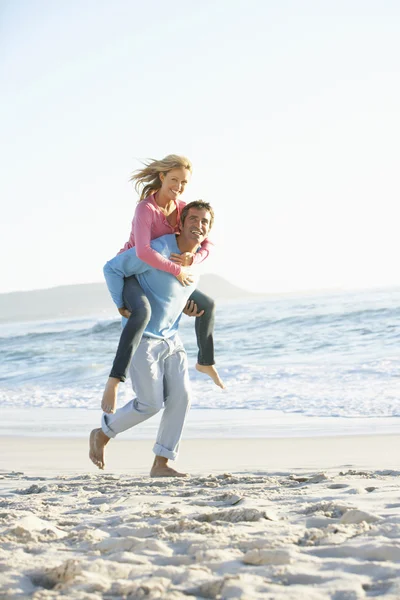 Uomo dando donna a cavalluccio sulla spiaggia — Foto Stock