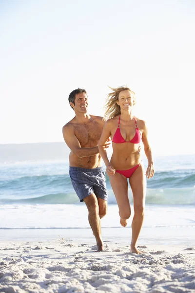 Paar läuft im Urlaub am Strand entlang — Stockfoto