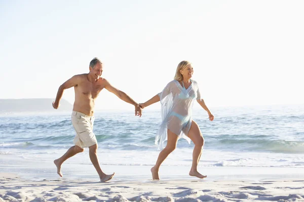 Casal sênior correndo ao longo da praia — Fotografia de Stock