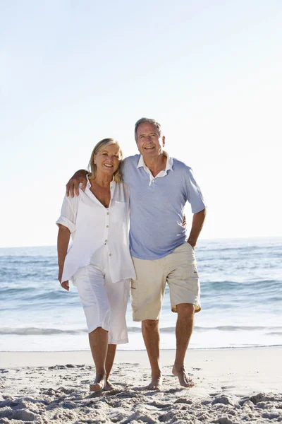 Couple aîné marchant le long de la plage — Photo