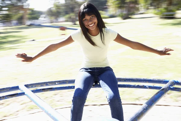 Fille assise sur le rond-point aire de jeux — Photo