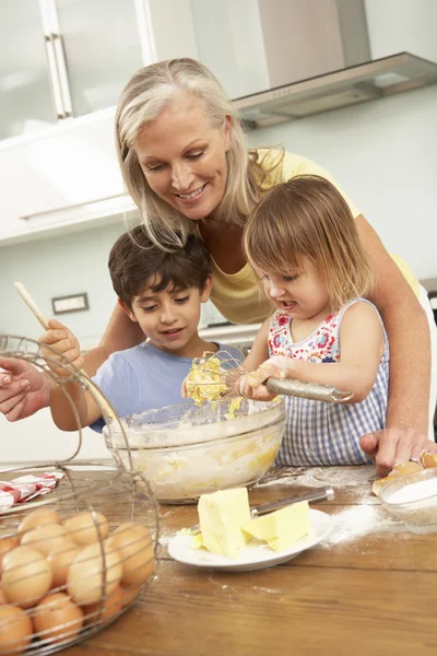 Kleinkinderen helpen grootmoeder taarten bakken — Stockfoto